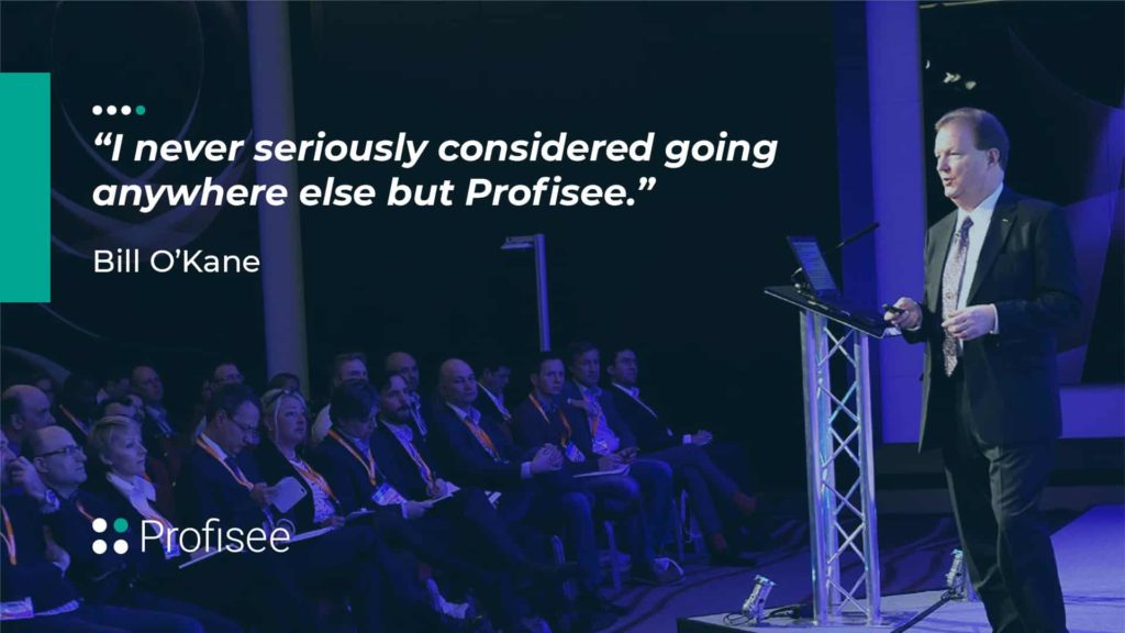 A speaker presents at a Profisee event, with a testimonial displayed on the screen.